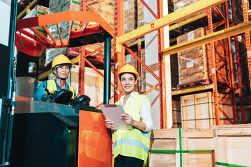 Asian woman warehouse Smiling worker standing with talking in large warehouse with goods and driver at Warehouse forklift loader works with goods.