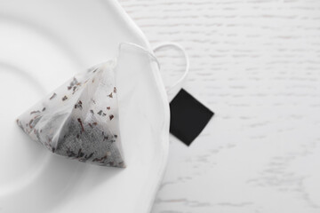 Pyramid tea bag on white table, top view. Space for text