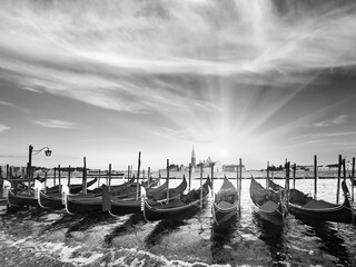 Grayscale. Parked gondolas on Piazza San Marco and The Doge's Palace embankment and sunset sunshine (Venice, Italy).