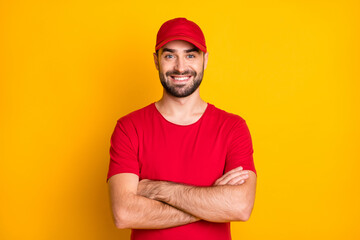 Portrait of attractive content virile cheerful guy mailman folded arms isolated over vibrant yellow...