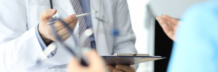 Doctor with phonendoscope holds pen and folder with documents in closeup conversation with another doctor. Medical advisory concept.