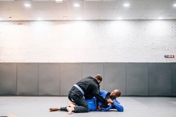 Two Jiu-Jitsu practitioners fighting on the mat in training