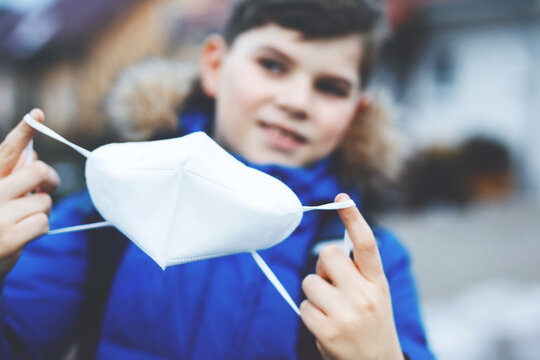 Kid boy wearing ffp medical mask on the way to school. Child backpack satchel. Schoolkid on cold autumn or winter day with warm clothes. Lockdown and quarantine time during corona pandemic disease