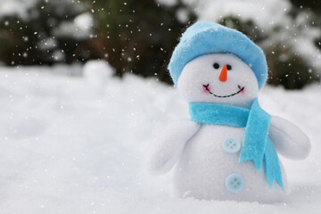 Cute small snowman toy on snow outdoors, space for text