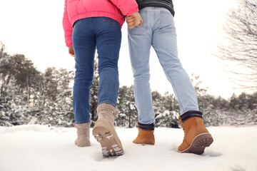Couple walking in snowy forest on winter day, closeup