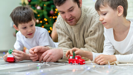 Dad and sons are playing near christmas tree
