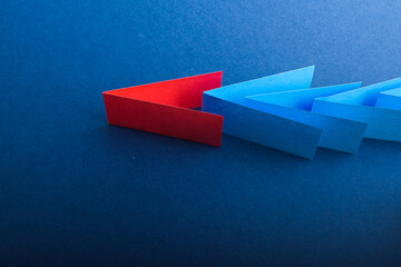 Multicolored cut paper on blue. Abstract arrows, direction signs.