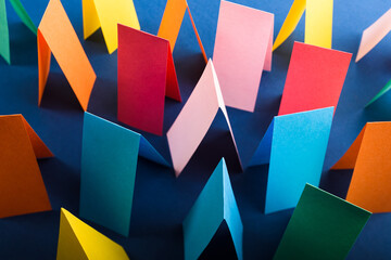 Multicolored cut paper on blue. Abstract arrows, direction signs.