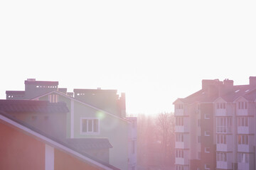 Selective focus roofs of houses on a background of sunrise. Bright rays of the sun between low-rise buildings