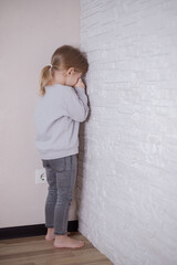 Child little girl standing in the corner of the room. Parental errors in raising children, improper punishment of children concept