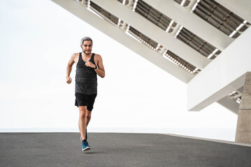 Obraz premium Young runner man doing workout routine at morning time while running outdoors in the city - Focus on face