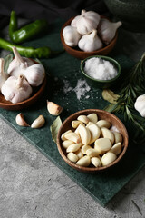Fototapeta na wymiar Bowls with garlic and salt on grey background