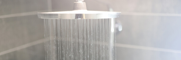 Hot water is poured from rain shower in bathroom. Bathroom plumbing concept.