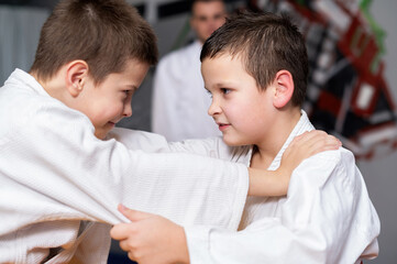 Two boys practice martial arts in a gym