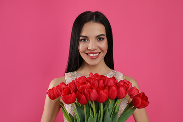 Happy woman with red tulip bouquet on pink background. 8th of March celebration