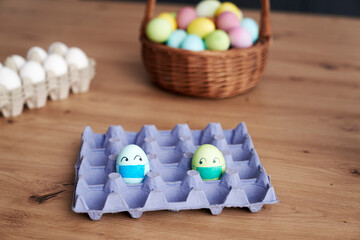 Fototapeta na wymiar Eggs with face masks in a cardboard box on the table