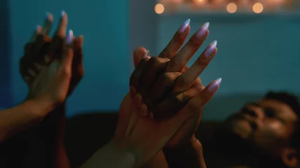 In love. Cropped shot of a passionate mixed race couple, man and woman holding hands while having sex in bedroom © Svitlana