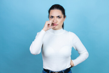 Young caucasian woman wearing white sweater over blue background mouth and lips shut as zip with...