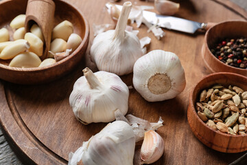 Board with fresh garlic and spices on wooden table