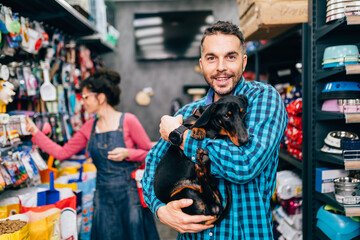 Happy couple buying toys and food for their Dachshund in pet shop.