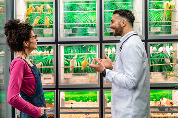 Female customer talking with veterinarian in pet shop about parrot she wants to buy.