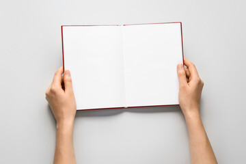 Female hands with blank book on light background