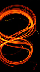 Abstract fiery pattern in the shape of the number 8. Drawing shapes with fire at night, infinity sign, bright colors on night background, fun with fire.