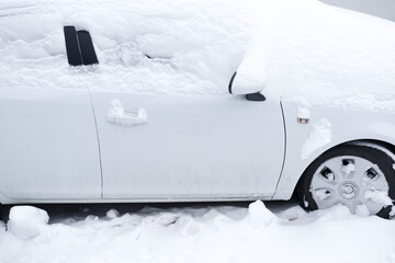white car covered with snow on the street.