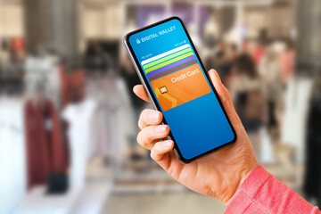 Woman using digital wallet on her mobile phone to pay wirelessly in store with her credit card