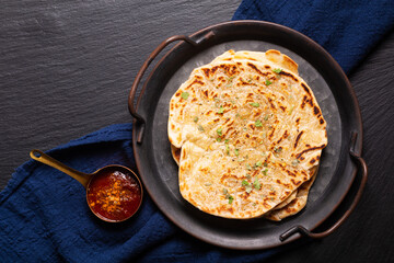 Food concept spot focus homemade Paratha, Parotta or Porotta layered flatbread  on black background with copy space