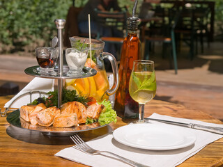lunch served on summer restaurant terrace in a sunny day. portion of grilled salmon fish fillet served with sauce and fresh vegetables eggplant, tomato and herbs paste. vertical photo