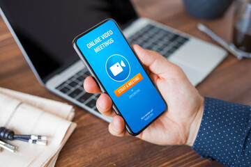 Man using online video meeting app on phone at work