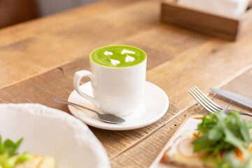 Healthy breakfast in the restaurant. Green salad, bruschetta with arugula and salmon and matcha latte