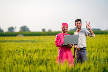 Young indian agronomist and farmer using laptop for seeing some information about farming