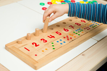 Child playing with different color wooden rings. Sequence, fine motor skills, therapy task for education and brain exercise. Counting math play game.  Montessori type implement. Wooden toys.