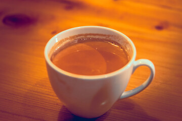 Hot milk tea in a white cup on wooden table