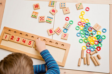 Child playing with different color wooden rings. Sequence, fine motor skills, therapy task for...
