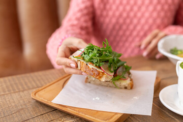 Woman in a restaurant in a cozy warm sweater wholesome breakfast with toast with arugula and salmon