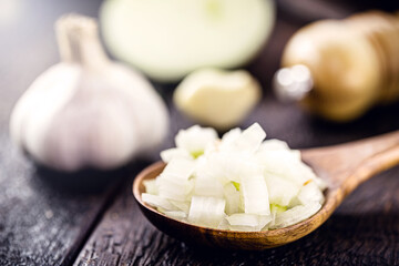 wooden spoon with chopped organic onion, with garlic clove in the background. Vintage rustic kitchen