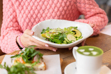 Healthy breakfast in the restaurant. Green salad, bruschetta with arugula and salmon and matcha latte