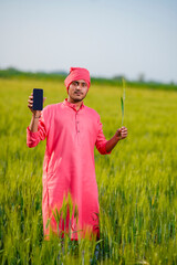 Indian farmer holding crop plant in his Wheat field