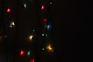 colorful light bulbs on a black background. garland for decoration for the holidays of Merry Christmas and Happy New Year.