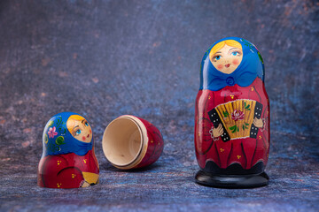 Matryoshka dolls in blue handkerchiefs, one open, with an accordion, and a balalaika on a dark...