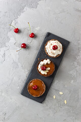 Raw cakes with coconut cream, cherries, almonds and banana. Sugar, gluten and lactose free. Vertical orientation, copy space.