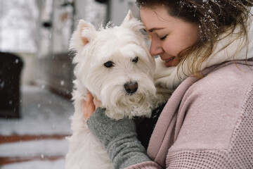 Nice laughing girl hugging adorable white dog with funny cute emotions.