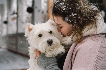 Nice laughing girl hugging adorable white dog with funny cute emotions.