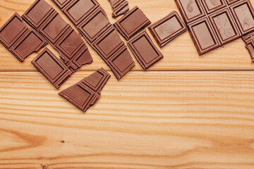 broken bar of chocolate on wooden background texture sweets