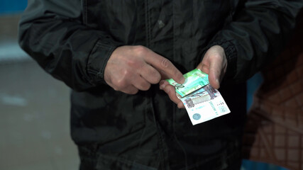A male worker of Caucasian nationality received Russian rubles for a working day. A male worker holds money in his hands and counts it