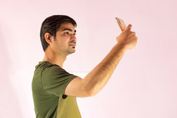 Young handsome Indian man taking selfie with mobile phone.
