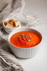 Pumpkin soup-puree with cream and seeds on a white background